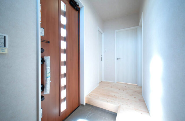 白基調の爽やかな空間に明るい木目の質感が溶け込む効率的な水回り動線の住まい - 感動 - 玄関