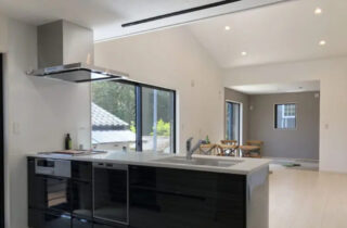 勾配天井の開放感とくすみブルーがアクセントのモノトーンで温もりを感じる平屋 - センチュリーハウス - キッチン