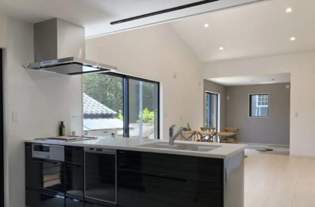 勾配天井の開放感とくすみブルーがアクセントのモノトーンで温もりを感じる平屋 - センチュリーハウス - キッチン