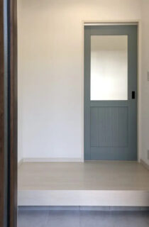 勾配天井の開放感とくすみブルーがアクセントのモノトーンで温もりを感じる平屋 - センチュリーハウス - 玄関