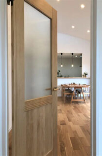 白と木目がやさしく調和する勾配天井の開放感と家事ラク動線を両立した平屋 - センチュリーハウス - LDKドア