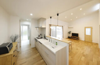 白と木目がやさしく調和する勾配天井の開放感と家事ラク動線を両立した平屋 - センチュリーハウス - キッチン