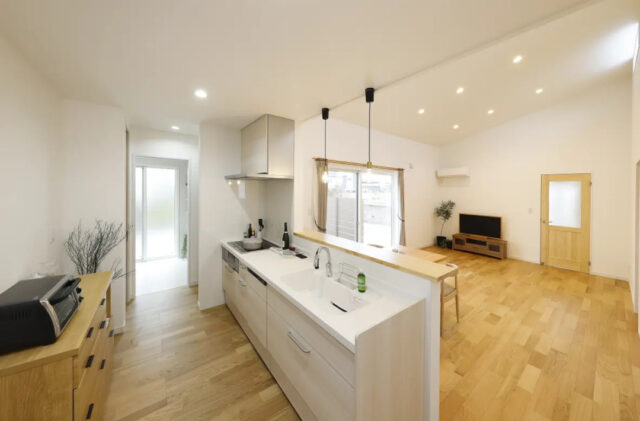 白と木目がやさしく調和する勾配天井の開放感と家事ラク動線を両立した平屋 - センチュリーハウス - キッチン