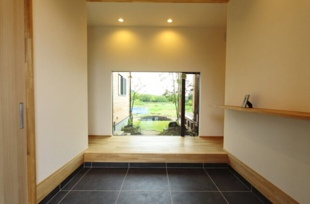 大開口の窓から庭を望むピクチャーウィンドウと木の温もりに満ちた平屋 - リブワーク - 玄関