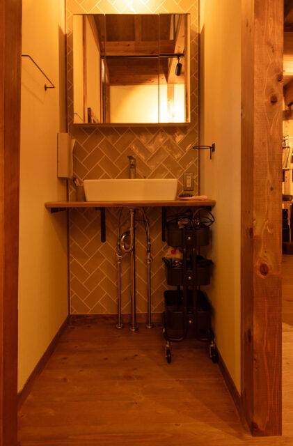 仕事も趣味も満喫するログハウス風の吹き抜けがある木の家 - サイエンスホーム - 洗面スペース