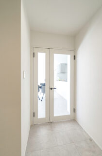 ブルーのガルバリウムと大屋根が映えるホテルライクなサロン付き平屋 - トータルハウジング - LDK扉