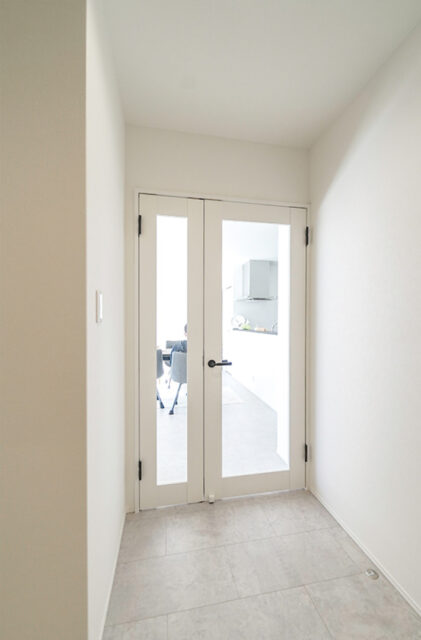 ブルーのガルバリウムと大屋根が映えるホテルライクなサロン付き平屋 - トータルハウジング - LDK扉